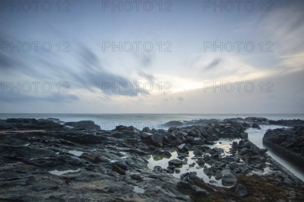 Beach, with lava rocks and vegetation, view of the sea in the evening at sunset. Landscape with clouds in Induruwa, Bentota Beach, Sri Lanka, India, Asia