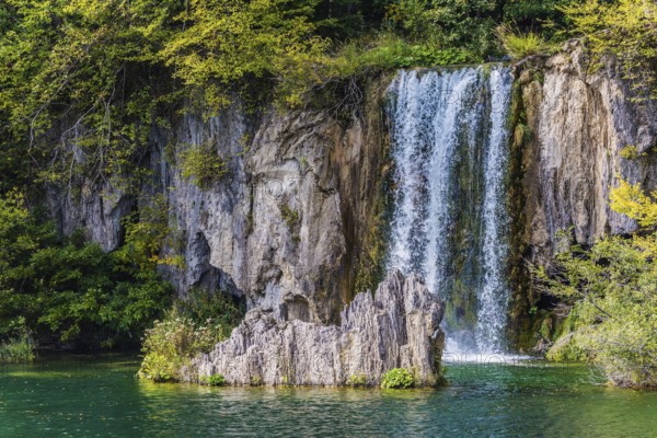 Charming little waterfall with a vertical ledge. Cascading Plitvice lakes in Croatia on a cloudy warm day. The concept of ecological, active and phototourism