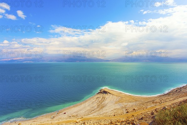 The smooth surface of the very salty sea water reflects the sky and clouds. Low winter clouds are reflected in the green sea water. Israel. Legendary Dead Sea