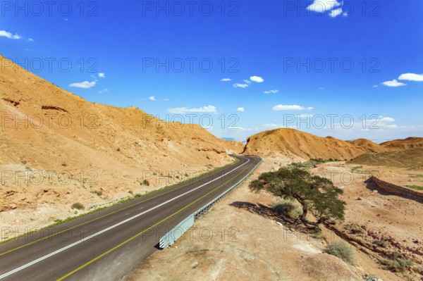 Straight as an arrow the road crosses the hills. Dry waterless hills of yelloy and beige clay. Judean desert on the shores of the Dead Sea. Israel. Shooting from drone