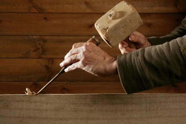 Gouge wood chisel carpenter tool hammer in hand working wooden background