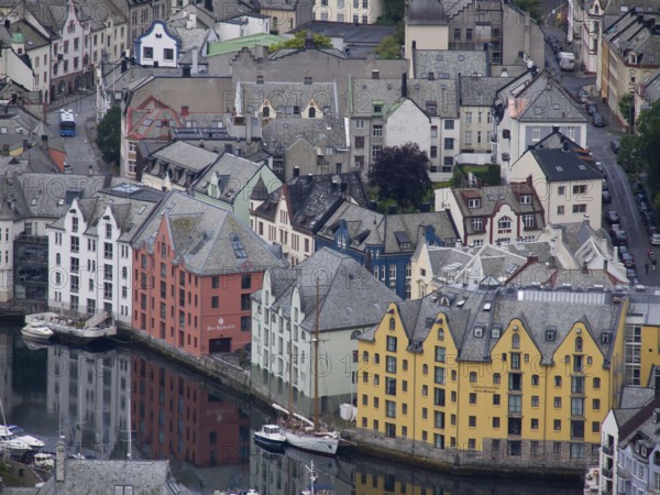 Colourful buildings on the harbour are reflected in the water. Historic architecture and Scandinavian style dominate the scene, alesund, norway
