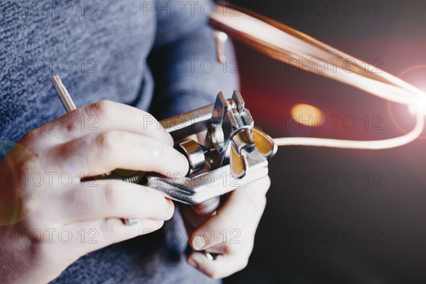 Hands using a mechanical tool with copper wire, emphasizing precision