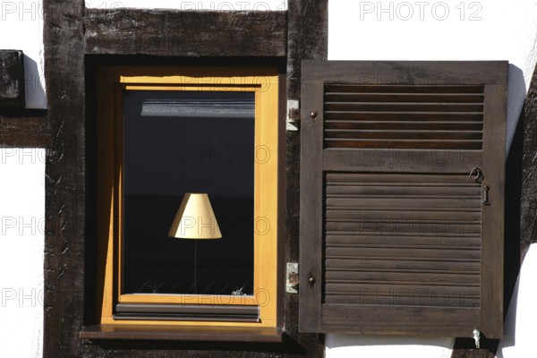 The nostalgic window of a half-timbered house with a lamp behind the window pane