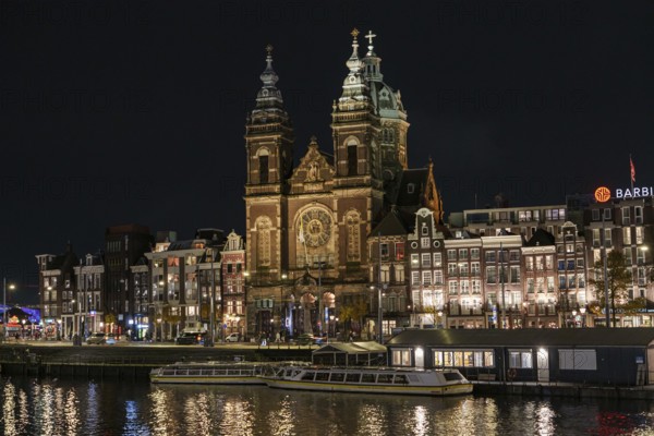 Night scene with illuminated church and surrounding buildings along a canal, Amsterdam, Netherlands