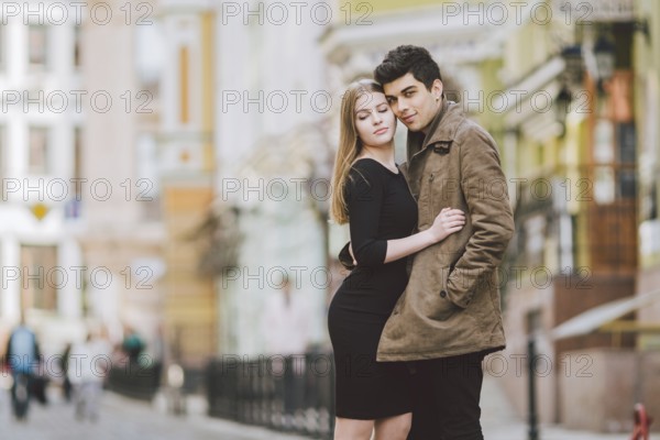 Urban modern young love couple walking romantic talking talking, holding hands on a date. Young multicultural Turkish brunette and Caucasian couple on old european street. Autumn spring weather