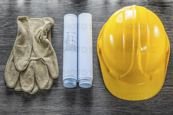 Safety gloves blueprints hard hat on wooden board