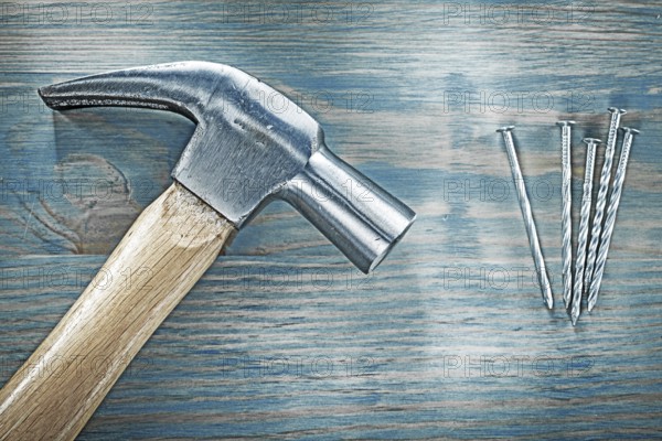 Horizontal view of claw hammer nails on wooden board construction concept
