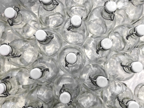 Transparent bottles seen from above. They can be filled with water, wine or other beverage. They are closed by a white plastic cap