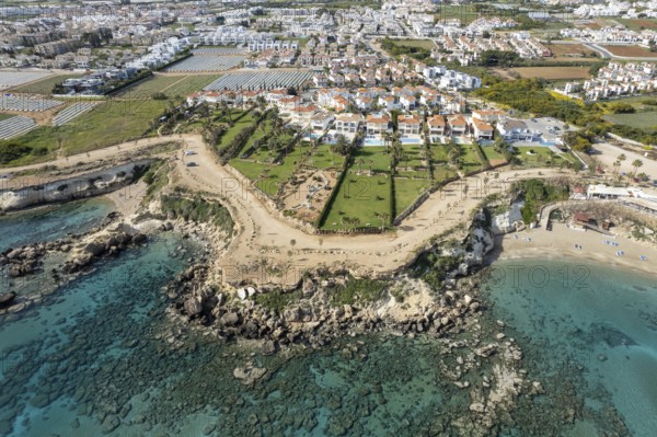 Drone aerial of holiday village with luxury houses at an idyllic rocky coast. Summer vacations at the sea. Protaras Cyprus