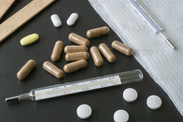 Traditional medical thermometer for measuring body temperature. Pills and medicaments on background. High body temperature