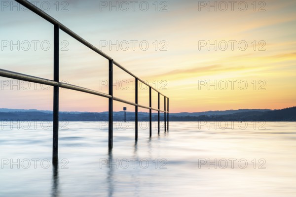 Railing in the lake at sunrise with gentle waves and peaceful sky, lido, Litzelstetten, Lake Constance, Baden-Württemberg, Germany, Europe