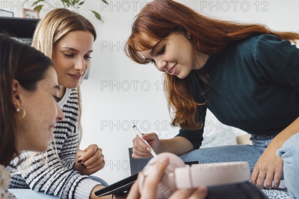 Group of three roommates, college student, young caucasian women, spending time together in their room, studying, talking, having fun, laughing