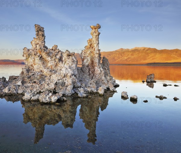 The magic of Mono Lake. Outliers - bizarre limestone formations reflected in the smooth water. Orange sunset
