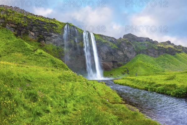 The warm July day in Iceland. Seljalandsfoss waterfall. Rainbow decorates drop of water
