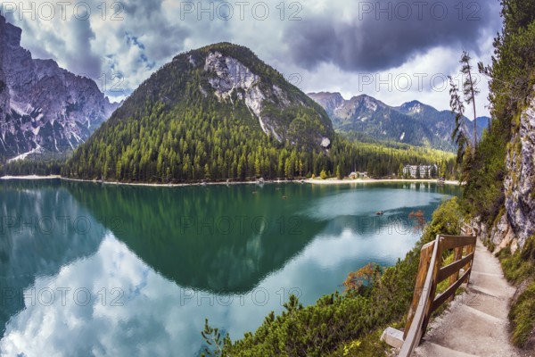 Magnificent Alpine lake Lago di Braies. Walking trail around the lake is fenced with wooden railings. The concept of environmental and hiking