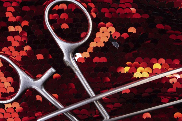 Detailed view of surgical instruments on shimmering red sequins