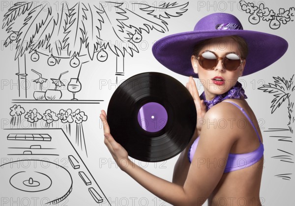 Colourful photo of a beautiful DJane in a bikini holding a retro vinyl record in her hands on a sketchy background of a DJ mixer and exotic landscape