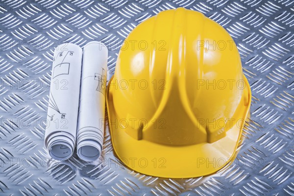 Rolled blueprints hard hat on grooved metal sheet construction concept