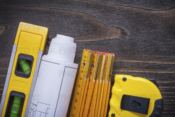 Roll of blueprints construction level tape-line and wooden meter on vintage wood board maintenance concept