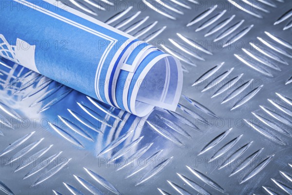 Blue rolled blueprints on corrugated metal background construction concept