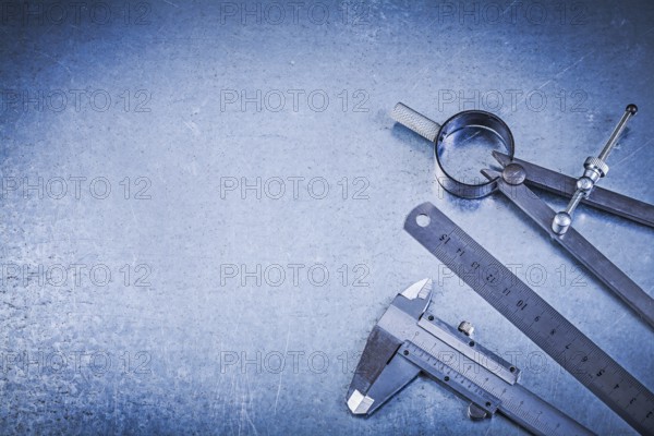 Metal construction drawing compass ruler caliper on metallic background