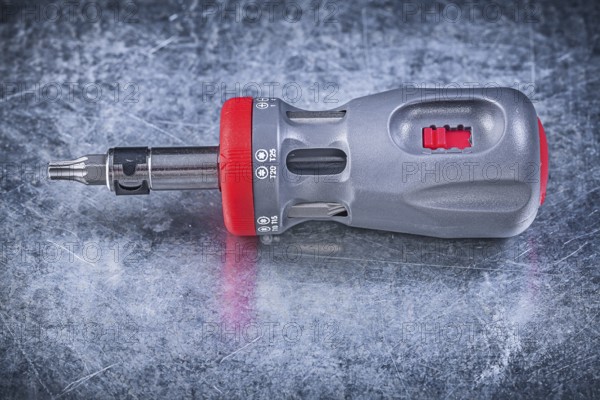 Screwdriver with replaceable bits on metallic background construction concept