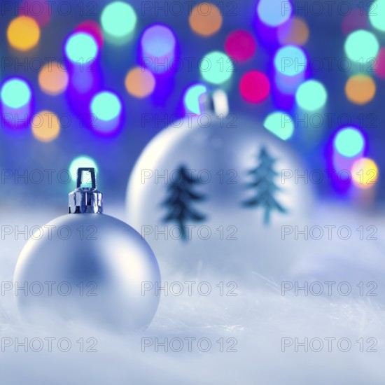 Christmas silver baubles witn tree and burred lights background