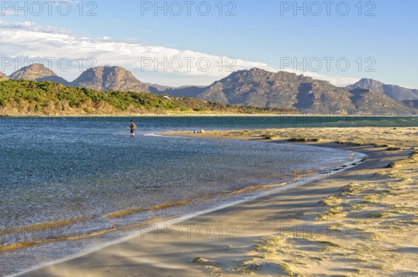 An angler in the shallow water on the Nine Mile Beach near Swansea with the Freycinet National Park in the distance, Tasmania, Australia, Oceania