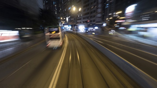 Traveling through the night city by double-decker tram. View to the rails and transport on the road. Shot in motion, Hong Kong, Asia