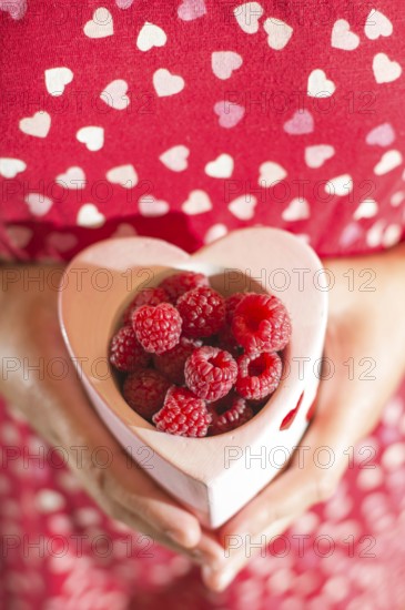 Woman in red dress holding a cup of raspberries