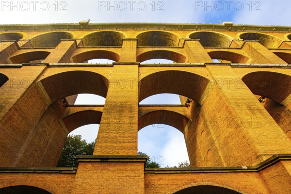 The Goltzsch Viaduct is the largest red brick viaduct in the world. Strong bridge supports. Germany.Cold morning in October. Magnificent huge bridge in a beautiful green park