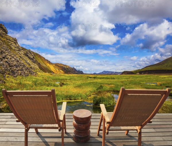 Two comfortable wooden chairs and small table stand for tired tourists. Volcanic summer tundra. Travel to Iceland in July