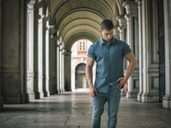 Handsome muscular young man standing outside in city setting looking to a side