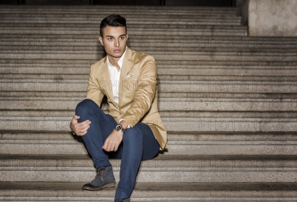 Elegant attractive young man outdoor wearing business suit, in European city on old stairs