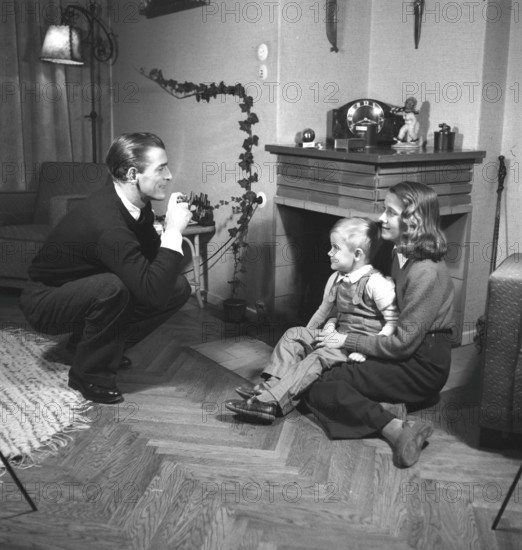 Amateur photographer in the 1940s A man is taking pictures of his wife and son at home. He is swedish actor singer Lasse Dahlquist. Sweden 1943. Kristoffersson Ref B27-4
