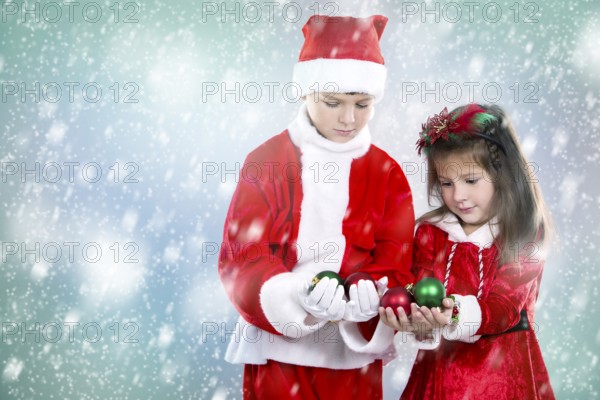 Couple of children holding christmas theme ornament on snowy background, Toronto, Canada, North America