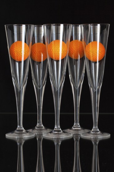 Five glasses of champagne and orange golf balls on the glass plate
