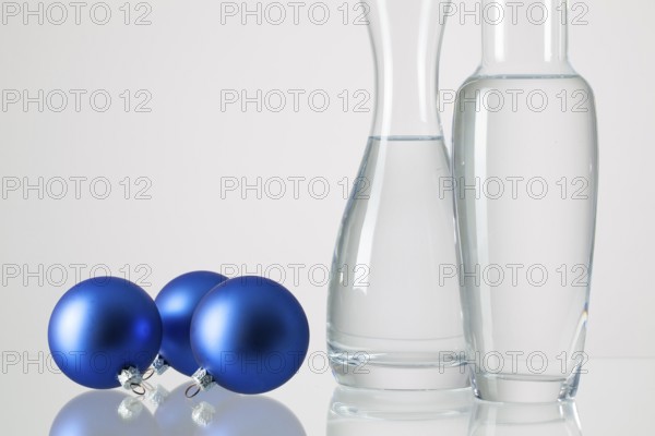 Two vases with clean water and Christmas decoration on a glass table