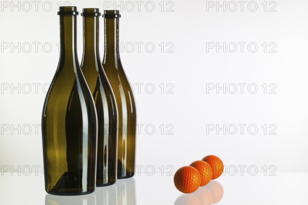 Empty three wine bottles and golf balls on a glass desk
