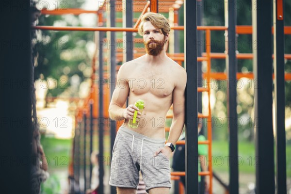 Thirst and health. Sportsman hold water bottle on stadium. Fit man with plastic flask outdoor. Stay hydrated and healthy. Sport and fitness