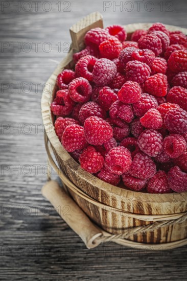 Bucket with fresh raspberries on wooden board