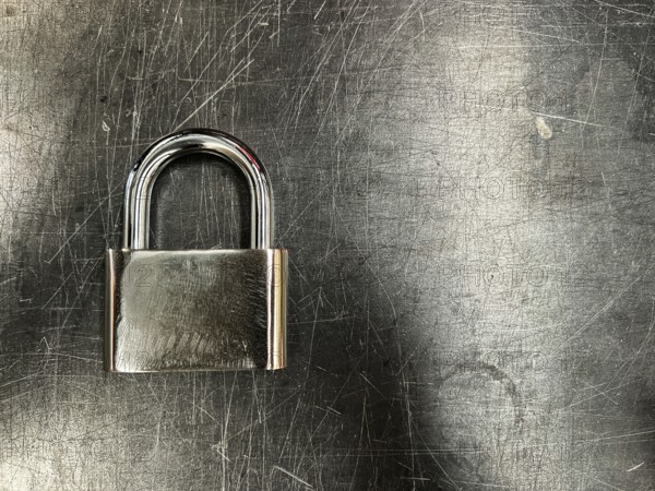 Metallic padlock on metal texture background