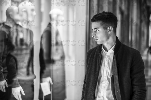 Handsome Young Man in Black Elegant Suit Looking at Displayed Fashion Items in Glass Window Boutique at the High Street Side
