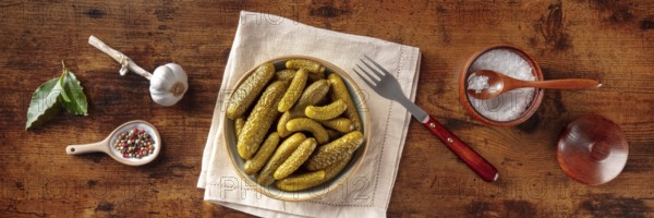 Pickled cucumbers with salt, pepper, garlic, and bay leaf panorama. Fermented food. Homemade canned gherkins. Overhead flat lay shot on a rustic wooden background, panoramic banner