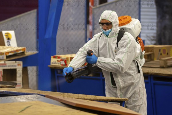 Sofia, Bulgaria - 7 April, 2020: Worker sprays disinfectant outside of ? food market against the spread of coronavirus disease COVID-19