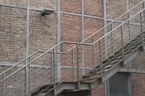 Metal fire escape climbing a brick wall with a lamp
