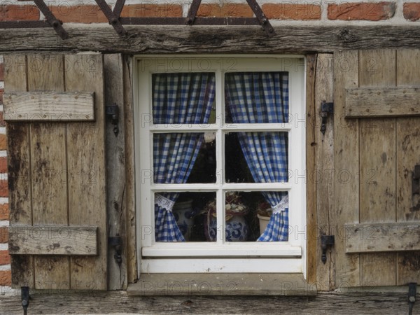 Rustic window with blue and white chequered curtains in a wooden frame, weseke, münsterland, germany
