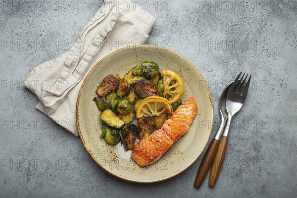 Delicious salmon fillet with grilled Brussels sprouts on plate, rustic stone background top view. Healthy dinner with grilled fish and vegetables, balanced nutrition, food photography, food photography