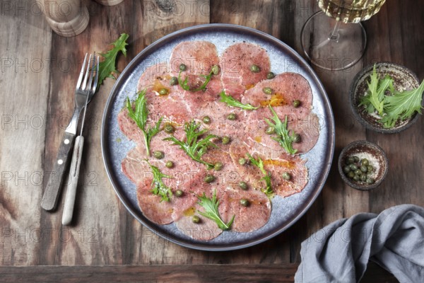 Food, Food, Marbled beef carpaccio with arugula and capers on gray plate with white wine, wooden background, top view